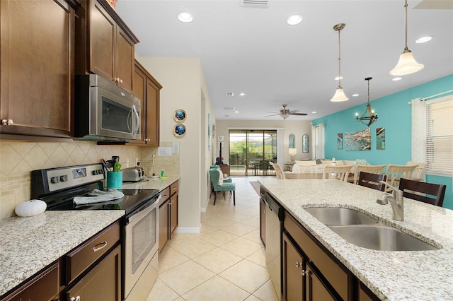 kitchen featuring light stone counters, stainless steel appliances, hanging light fixtures, sink, and ceiling fan