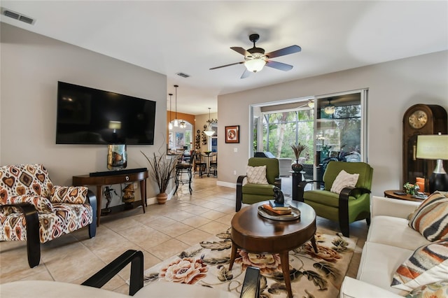 tiled living room with ceiling fan with notable chandelier