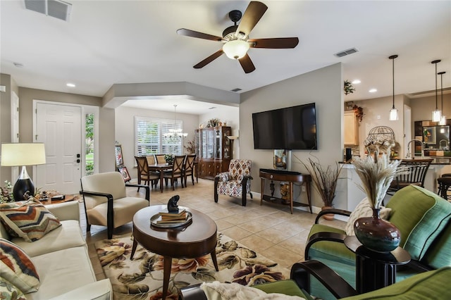 tiled living room with ceiling fan with notable chandelier