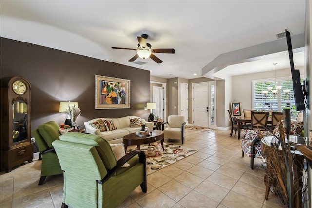 tiled living room with ceiling fan with notable chandelier