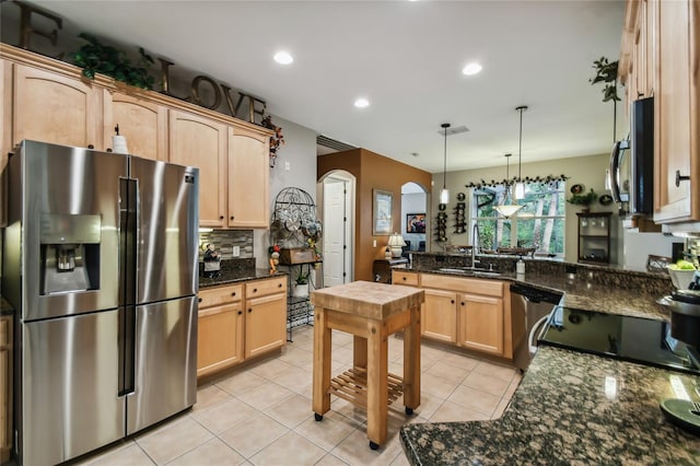 kitchen with light brown cabinets, appliances with stainless steel finishes, sink, and hanging light fixtures