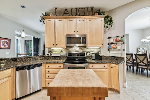 kitchen featuring stainless steel appliances, light brown cabinetry, pendant lighting, and a kitchen island