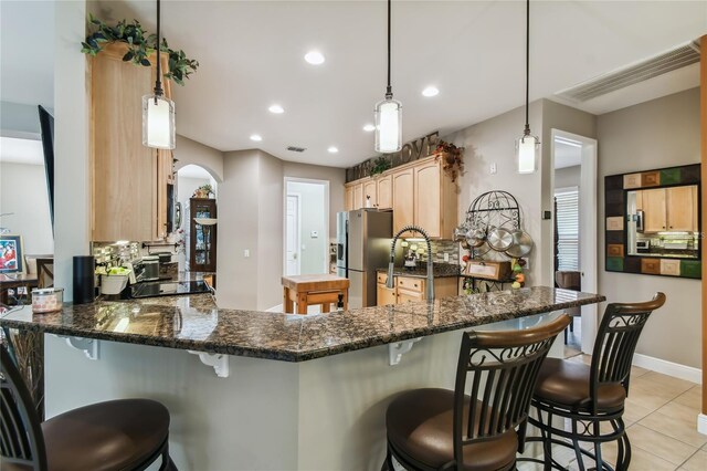 kitchen featuring backsplash, stainless steel fridge, decorative light fixtures, and a breakfast bar