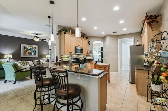 kitchen with appliances with stainless steel finishes, kitchen peninsula, ceiling fan, light tile patterned floors, and pendant lighting