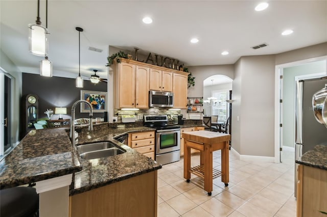 kitchen featuring stainless steel appliances, hanging light fixtures, sink, ceiling fan, and light brown cabinets