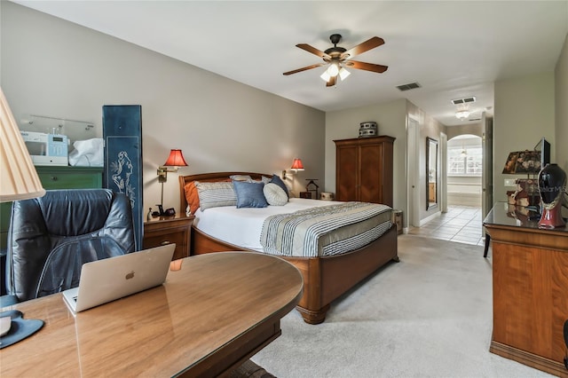 bedroom with ceiling fan, ensuite bath, and light carpet