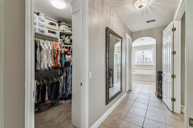 hall featuring light tile patterned flooring and a notable chandelier