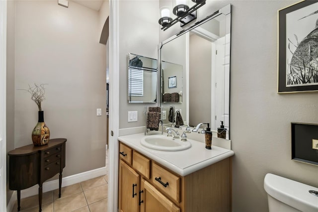 bathroom with toilet, vanity, and tile patterned flooring