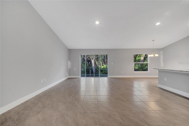 spare room with light tile patterned floors, a chandelier, and vaulted ceiling