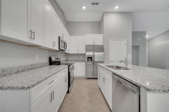 kitchen with sink, light stone countertops, an island with sink, appliances with stainless steel finishes, and white cabinetry