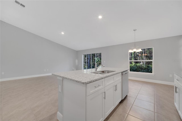 kitchen featuring light stone counters, sink, dishwasher, white cabinetry, and an island with sink