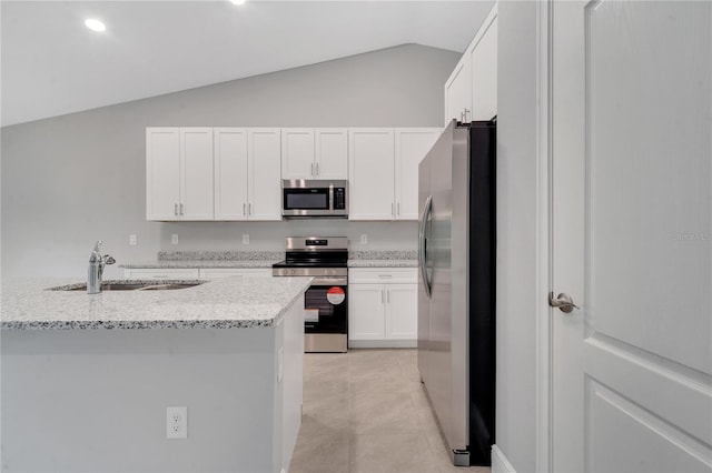 kitchen with white cabinets, sink, vaulted ceiling, light stone counters, and stainless steel appliances