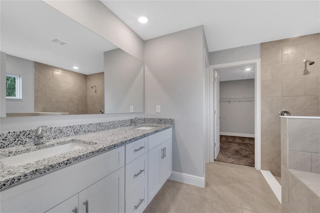 bathroom with tile patterned flooring, vanity, and tiled shower