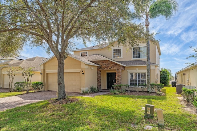 view of property featuring a garage, central air condition unit, and a front lawn