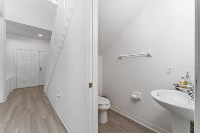 bathroom featuring toilet, sink, wood-type flooring, and a textured ceiling