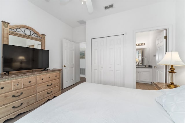 bedroom featuring a closet, light hardwood / wood-style floors, ceiling fan, and connected bathroom