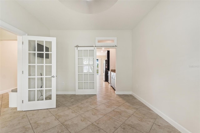 spare room featuring a barn door, light tile patterned floors, and french doors