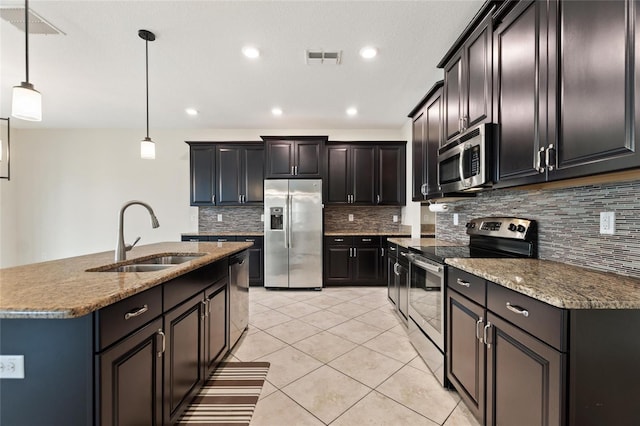 kitchen with stainless steel appliances, a center island with sink, sink, light tile patterned floors, and decorative light fixtures