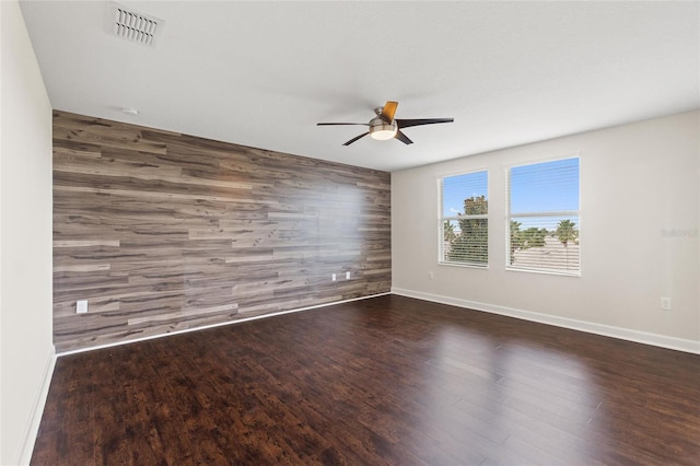 unfurnished room with dark hardwood / wood-style flooring, wooden walls, and ceiling fan