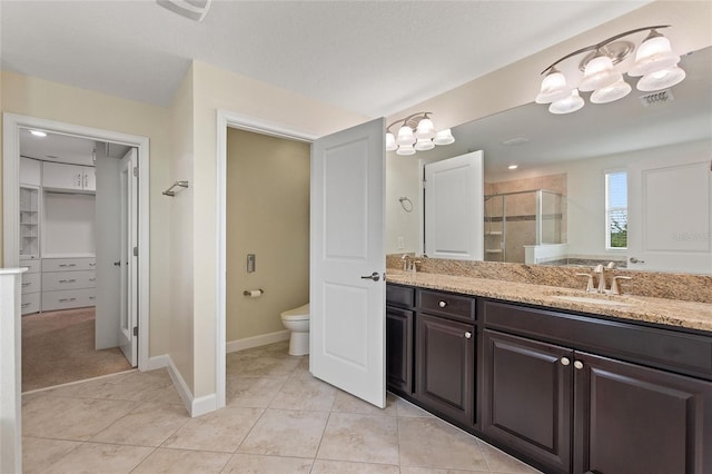 bathroom featuring toilet, tile patterned flooring, a textured ceiling, vanity, and a shower with shower door