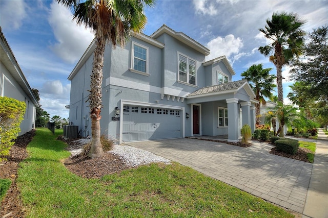 view of front of house with a garage, cooling unit, and a front lawn