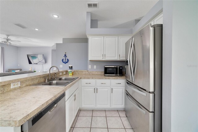 kitchen featuring stainless steel appliances, kitchen peninsula, sink, light tile patterned flooring, and white cabinetry