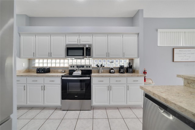 kitchen with white cabinetry, light tile patterned floors, and stainless steel appliances