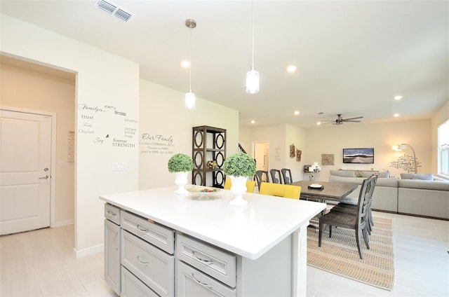 kitchen with a center island, gray cabinets, hanging light fixtures, and ceiling fan