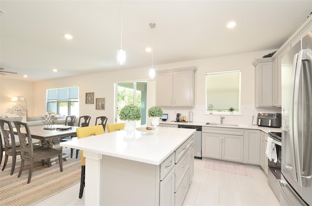 kitchen with sink, decorative light fixtures, a breakfast bar, a kitchen island, and appliances with stainless steel finishes