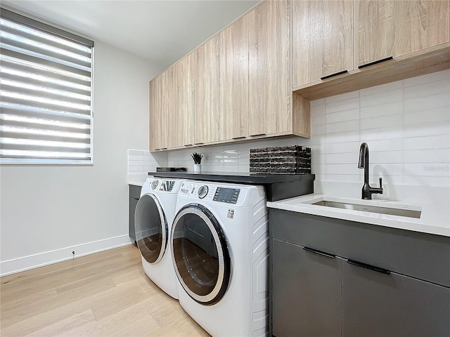 clothes washing area with sink, light wood-type flooring, cabinets, and independent washer and dryer