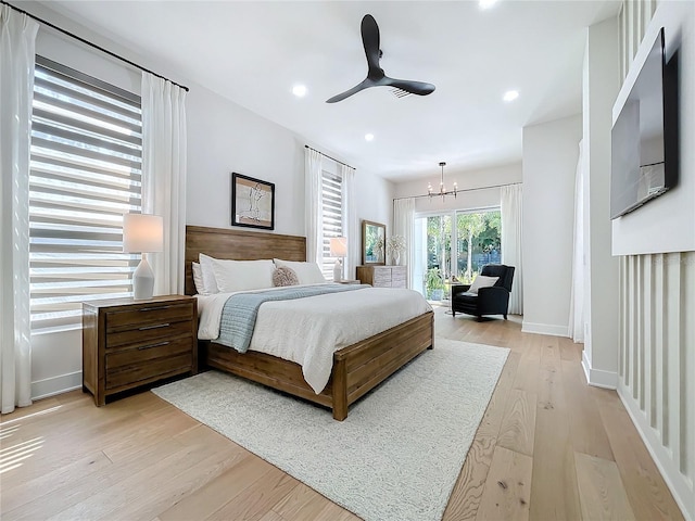 bedroom with ceiling fan with notable chandelier and light hardwood / wood-style flooring