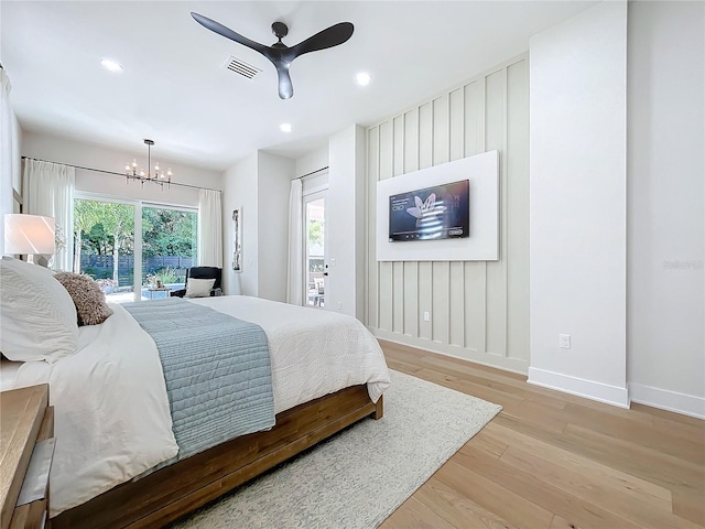 bedroom with access to outside, ceiling fan with notable chandelier, and light hardwood / wood-style flooring