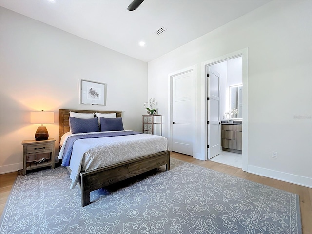 bedroom featuring light hardwood / wood-style floors, ceiling fan, and ensuite bath