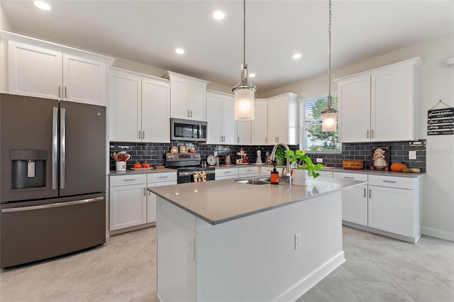 kitchen with white cabinets, an island with sink, pendant lighting, and appliances with stainless steel finishes