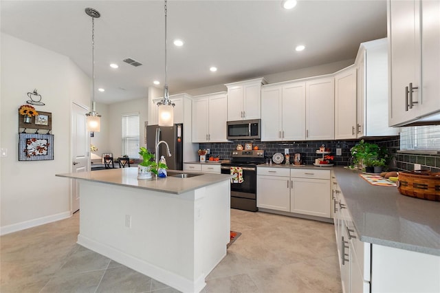 kitchen with white cabinetry, sink, appliances with stainless steel finishes, an island with sink, and hanging light fixtures