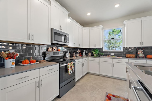 kitchen with backsplash, appliances with stainless steel finishes, light tile patterned flooring, and white cabinets