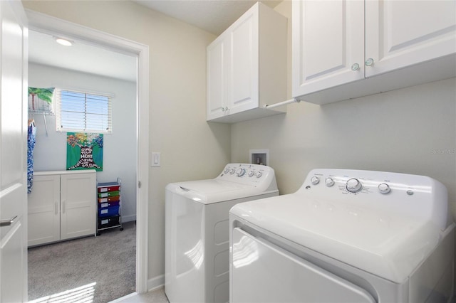 laundry room with cabinets, washing machine and clothes dryer, and light carpet