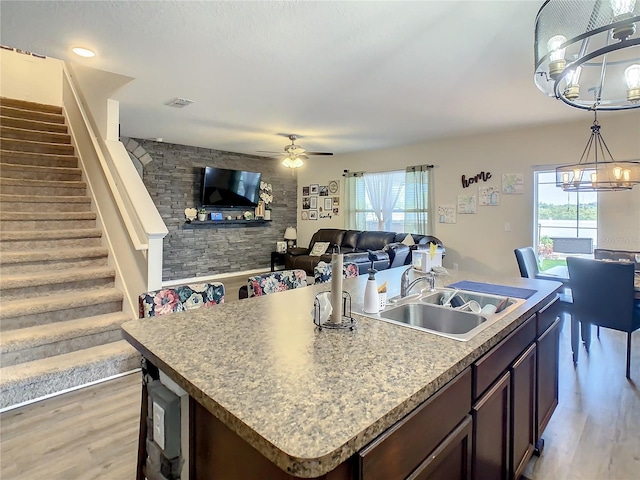 kitchen with dark brown cabinets, light hardwood / wood-style floors, a center island with sink, and sink