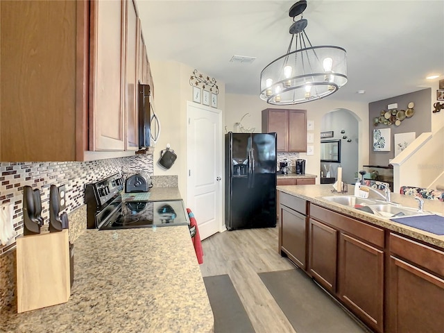 kitchen with stainless steel appliances, backsplash, hanging light fixtures, light hardwood / wood-style flooring, and a notable chandelier