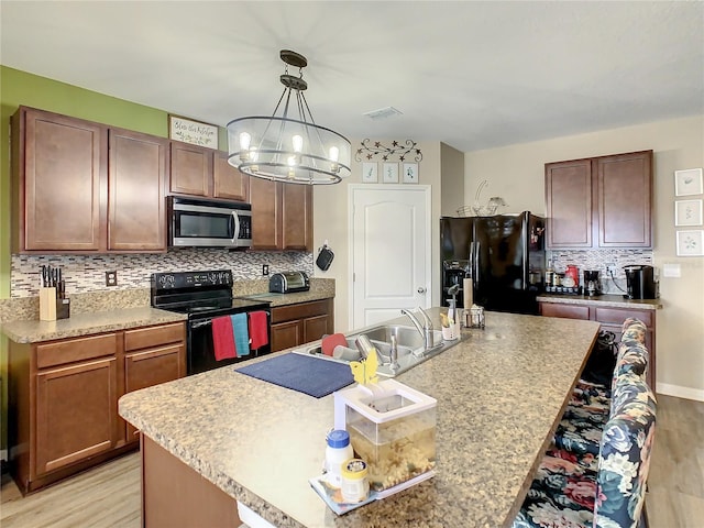 1927 Partin Terrace Rd, Kissimmee, FL 34744 - kitchen with black appliances, a sink, light wood-style floors, a chandelier, and backsplash