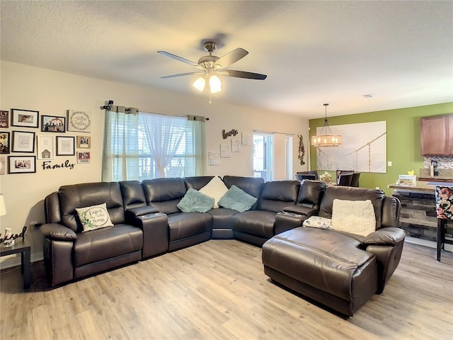 living room with light hardwood / wood-style floors and ceiling fan with notable chandelier