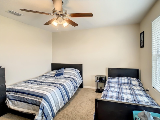 bedroom featuring ceiling fan, multiple windows, and light carpet