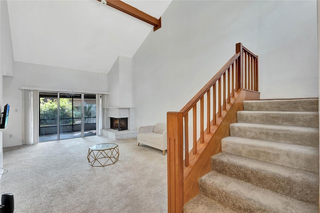 carpeted living room featuring beam ceiling, high vaulted ceiling, and a brick fireplace