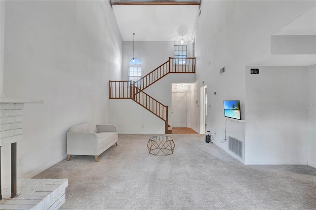 foyer with light carpet, a fireplace, and a high ceiling