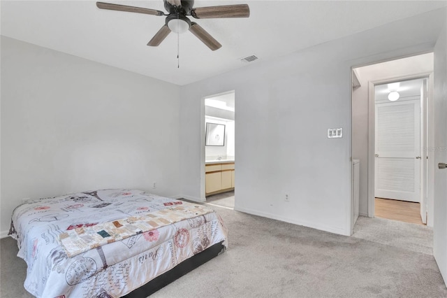 bedroom with ensuite bath, ceiling fan, and light colored carpet