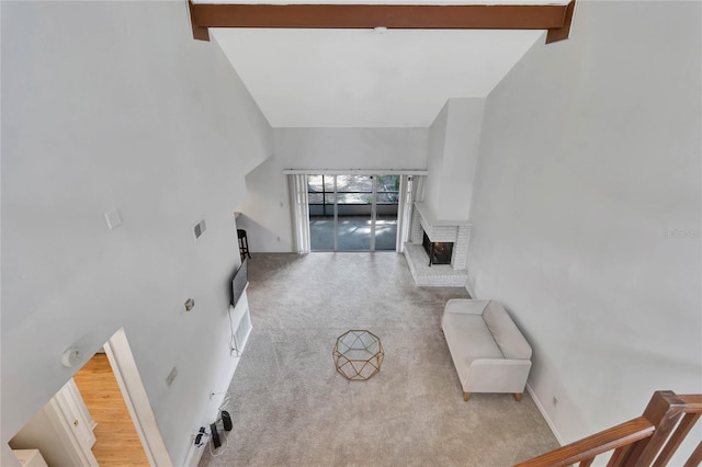 carpeted living room featuring beam ceiling, high vaulted ceiling, and a brick fireplace