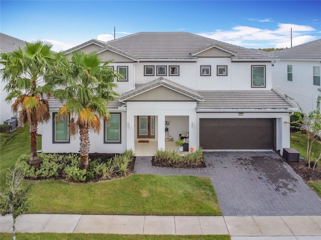 view of front of house featuring cooling unit, a garage, and a front lawn