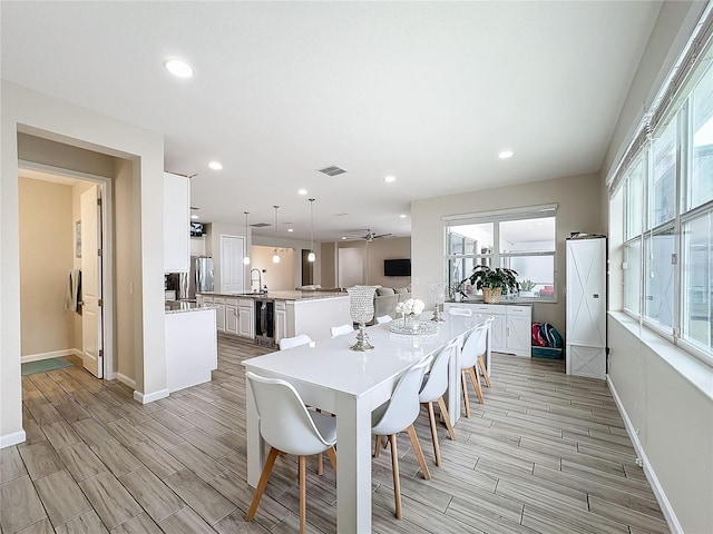 dining space featuring light hardwood / wood-style floors, ceiling fan, and sink