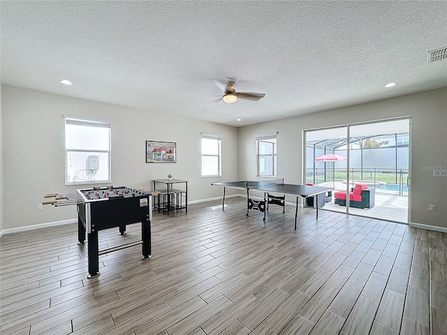 game room with ceiling fan, a textured ceiling, and light hardwood / wood-style flooring