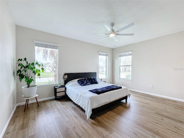 bedroom with ceiling fan, a textured ceiling, and light hardwood / wood-style flooring